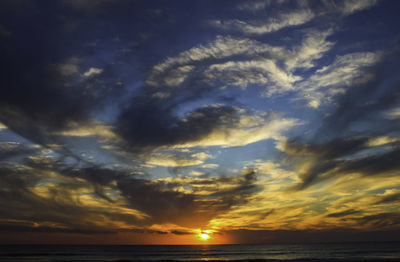 Scenic view of sea against dramatic sky during sunset