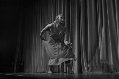 Rear view of woman standing against curtain