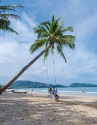 Rear view of woman standing on beach against sky