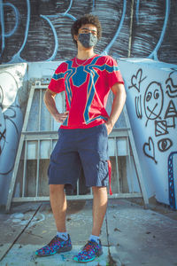 Portrait of boy standing against graffiti wall