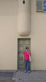 Full length of woman standing on footpath against building