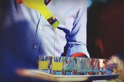 Midsection of man pouring alcohol in shot glass at bar