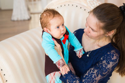 Rear view of mother and daughter sitting on floor