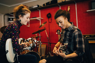 Friends playing guitars while practicing at recording studio