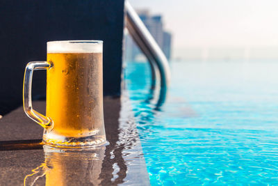 Close-up of beer glass on table by swimming pool
