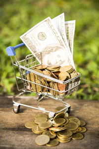 Close-up of coins in miniature shopping cart on table