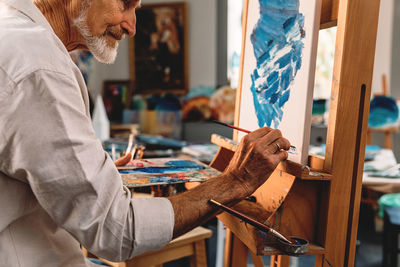 Side view of senior man painting on easel