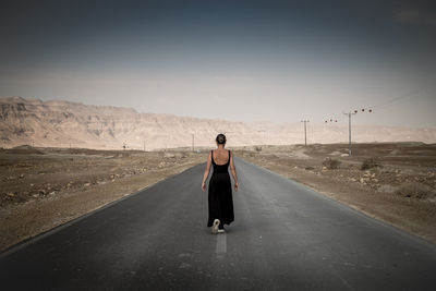 Rear view of woman walking on road