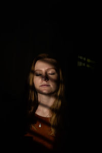 Teenage girl with eyes closed sitting in darkroom at home