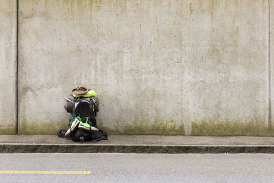 Backpack with personal accessories on footpath against wall