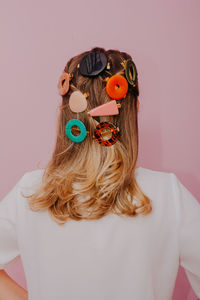 Rear view of woman wearing hair clips against pink background