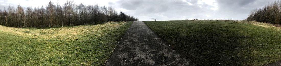 Panoramic view of road amidst field against sky