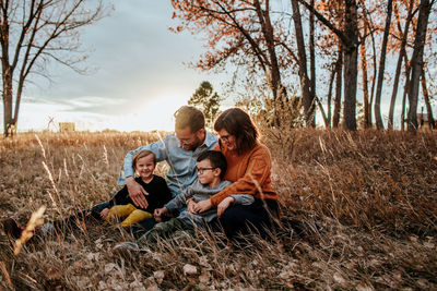 Smiling young family snuggling in a field on a fall evening