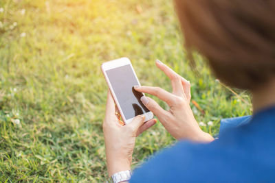 Cropped image of woman using phone on grassy field