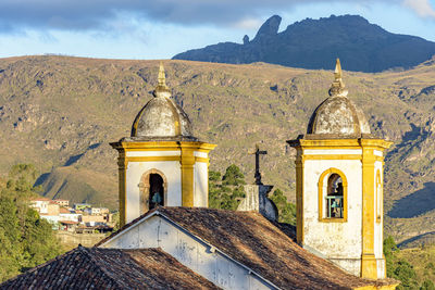 Historic church tower in baroque architecture with mountains in the background in ouro preto