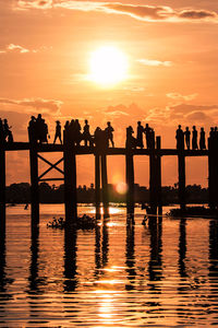 Silhouette people against orange sky during sunset