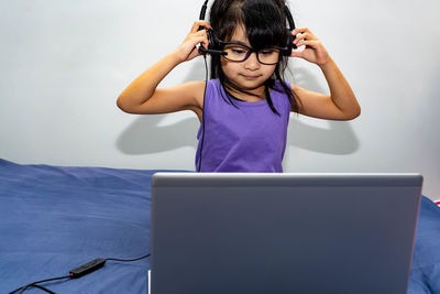 Girl wearing headphones while using laptop