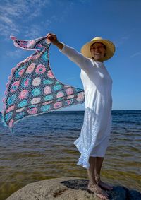 Woman standing by sea against sky