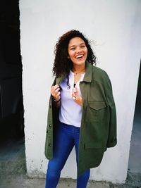 Smiling young woman standing against wall