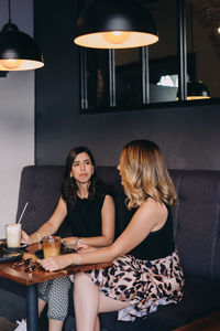 Young woman sitting on table at illuminated lamp