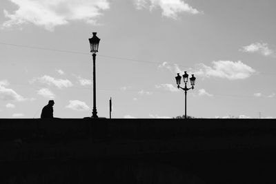 Silhouette man on street against sky