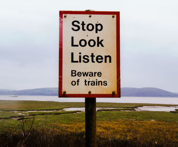 Close-up of warning sign on landscape against sky