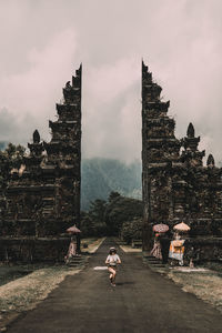 Mid adult woman posing on road leading towards temple entrance