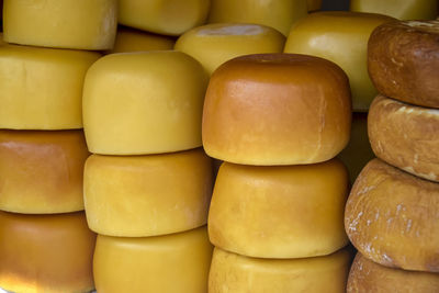 Cheese heads of different colors and sizes are stacked on table. fair trade in homemade cheese.