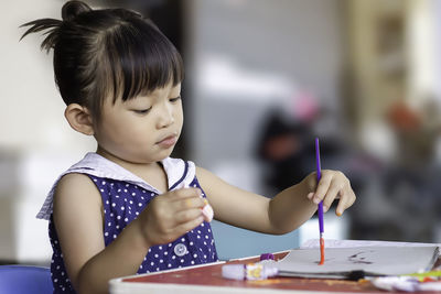 Girl holding ice cream on table