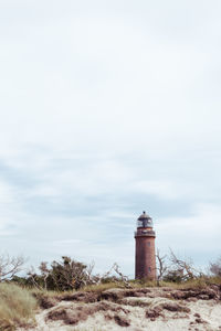 Lighthouse by sea against sky