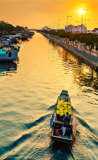 Man on boat moored on river against sky during sunset