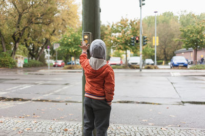 Rear view of man standing on sidewalk