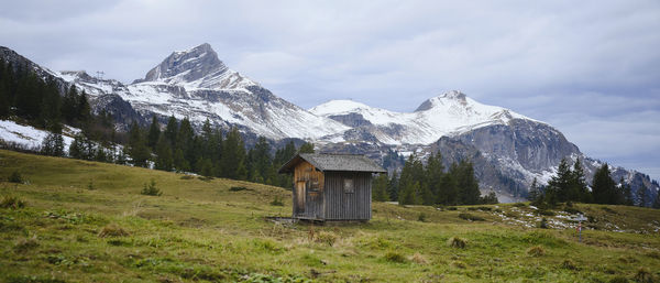 Scenic view of small hut against snowcapped mountains