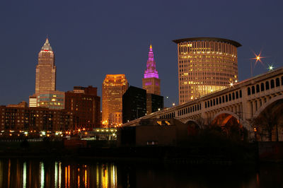 Detroit avenue bridge over river against illuminated modern buildings at night