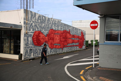 Rear view of man walking on road against buildings