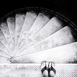 Low section of woman standing in metallic spiral staircase