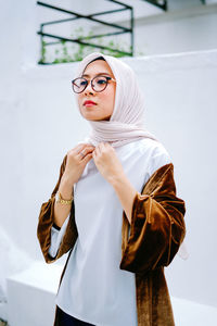 Young woman wearing mask standing against white background