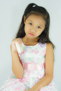 Portrait of a smiling girl standing against white background