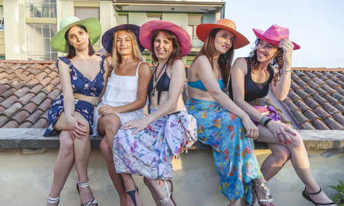 Portrait of smiling friends sitting on rooftop