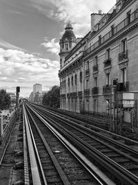 Railroad tracks in city against sky