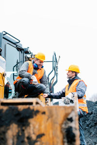 People sitting by earth mover in coal mine