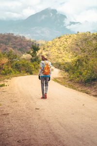 Rear view of woman walking on road against mountain