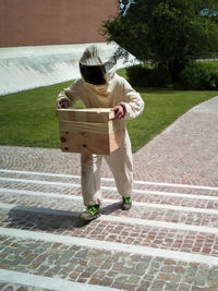 Beekeeper with overalls and protective suit with a box full of dangerous bees.