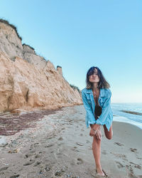 Young woman on beach against clear sky