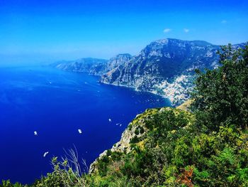 Scenic view of sea and mountains against clear blue sky