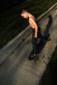 High angle view of shirtless boy standing on skateboard