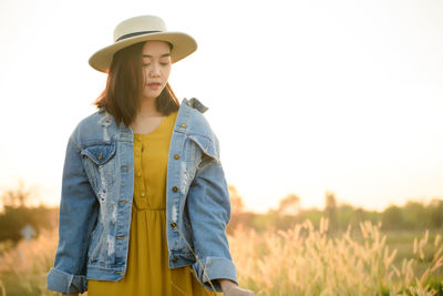 Woman wearing hat standing on field against sky