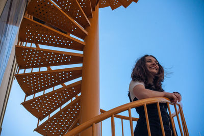 Low angle view of woman standing on steps against sky