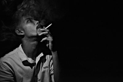 Man smoking cigarette against black background