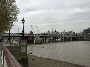 Bridge over river against cloudy sky